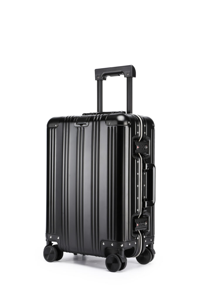 Ein schlanker, schwarzer Hartschalen-Schutzkoffer mit vier Spinner-Rollen, einem verstellbaren Teleskopgriff und horizontalen Rillen. Dieser moderne Koffer steht aufrecht und wirkt robust - ideal für Reisen und Sonderanfertigungen.