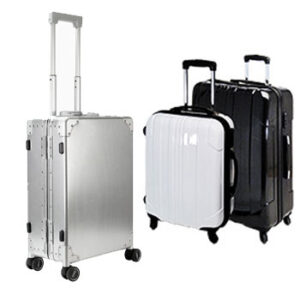 Three upright wheeled suitcases with extended handles are shown. One suitcase is metallic silver, while the other two are glossy; one white and one black. All have hard-shell exteriors and four wheels.